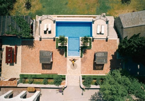 Woman laid her head on man stomach while lying sunbathing by the pool in the yard. Drone. High quality photo